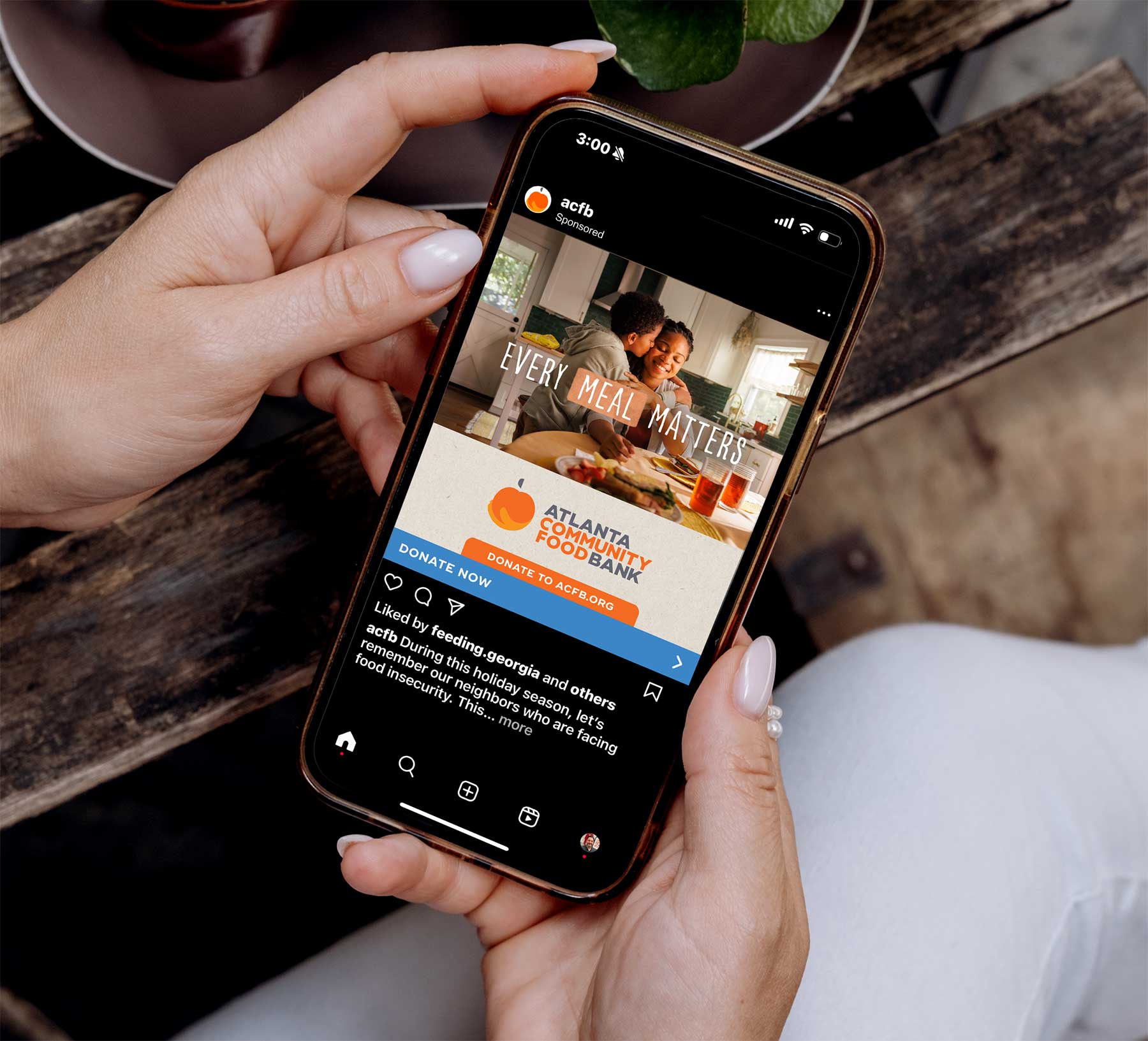 woman holding a cellphone featuring a sponsored ad from Atlanta Community Food Bank