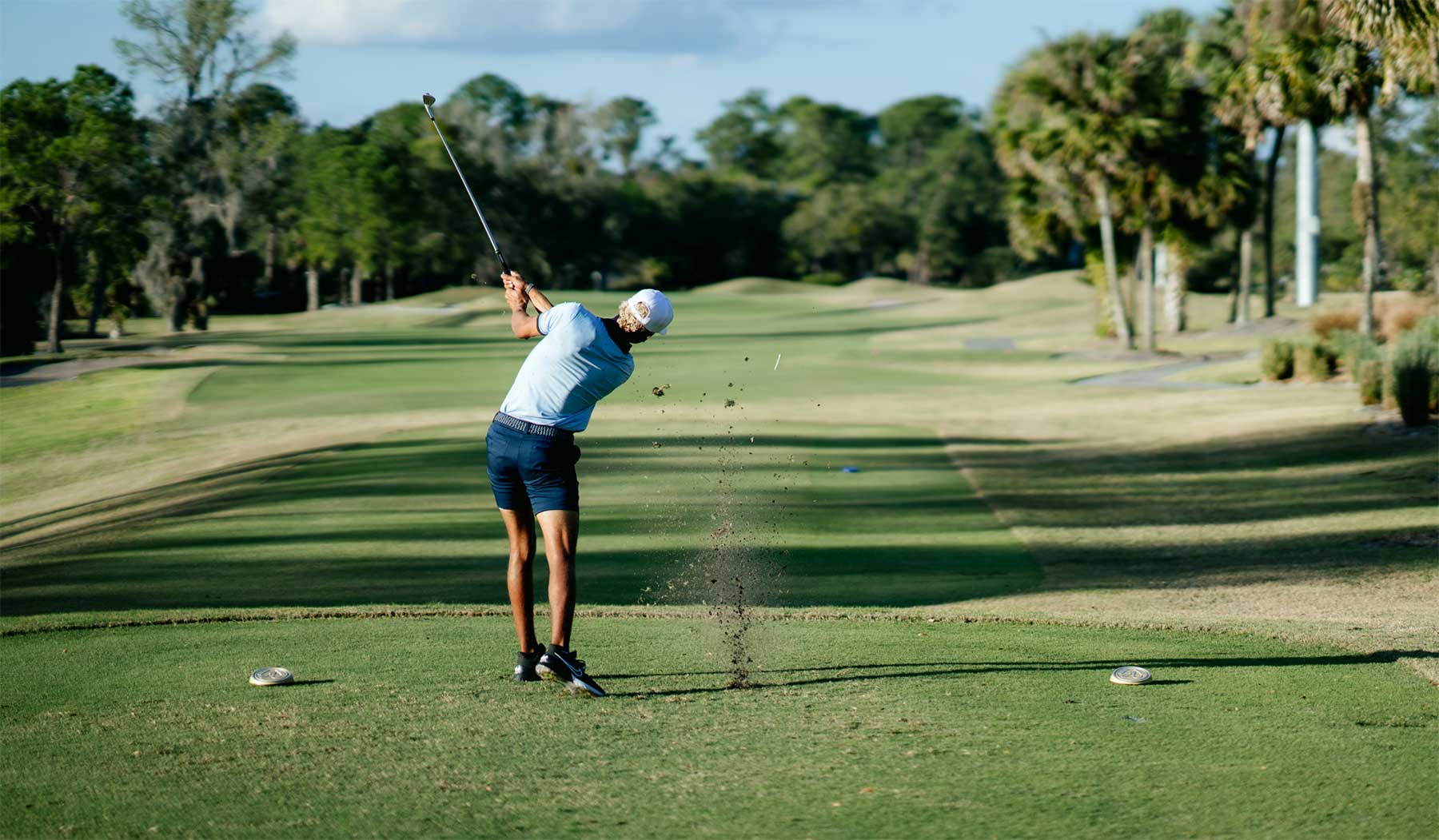 golfer hitting opening drive down a fairway