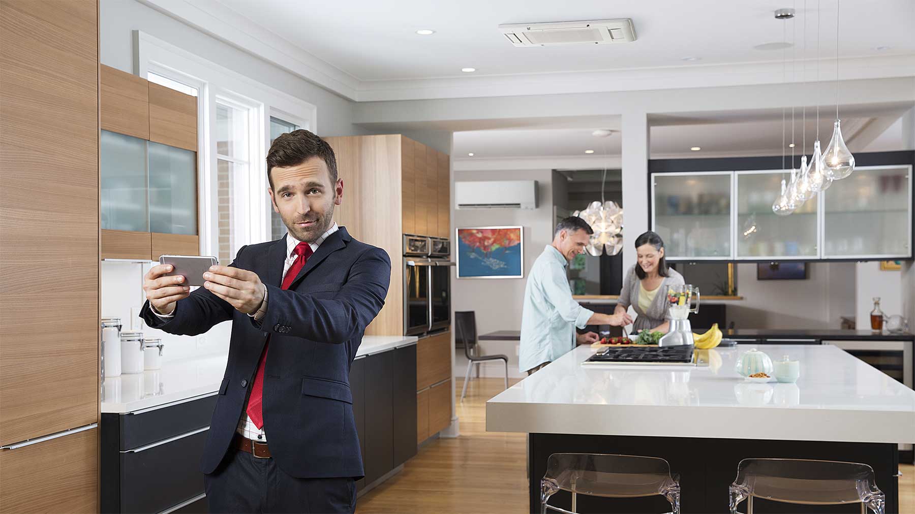 Mitsubishi Electric spokesperson taking a selfie in a kitchen with a couple in the background