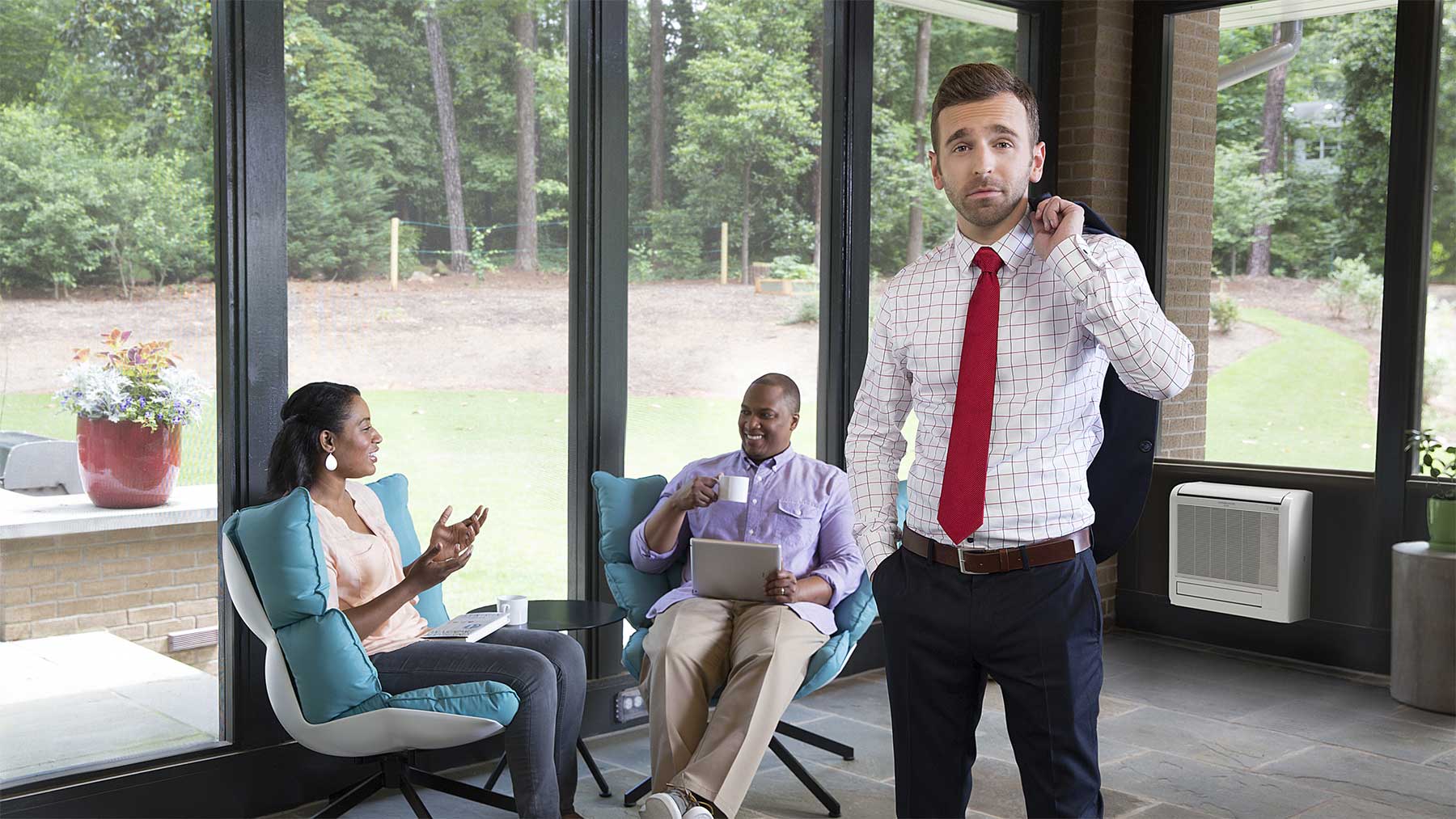 Mitsubishi Electric spokesperson stadning in a sunroom with a couple having coffee