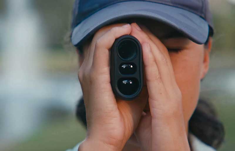 woman golfer looking through a rangefinder